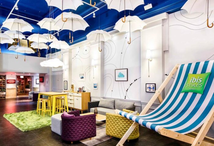 ibis Styles Manchester Portland lobby. Gay-friendly hotel with unique umbrella decor, beach chair, and colorful furniture. Great for gay travel.
