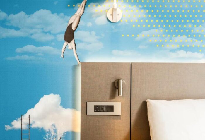 Ibis Styles Manchester Portland gay-friendly hotel room. The wall features a swimmer diving into a sky with clouds and a ladder. Modern design.
