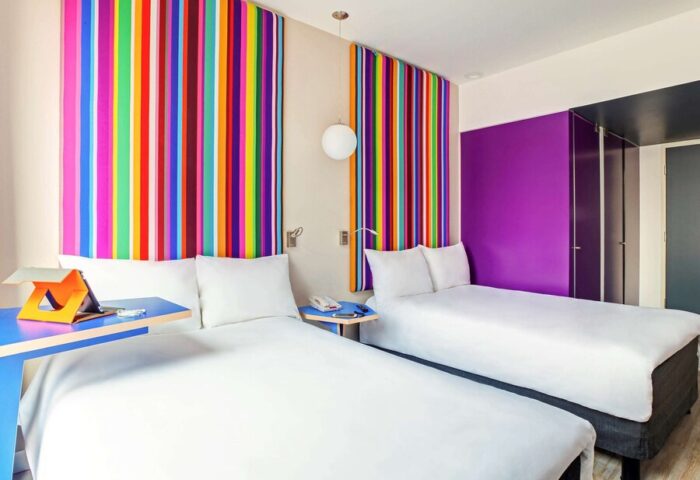 Ibis Styles Mexico Reforma gay-friendly hotel room. Twin beds, colorful striped wall art, and vibrant decor. Perfect for gay travelers.
