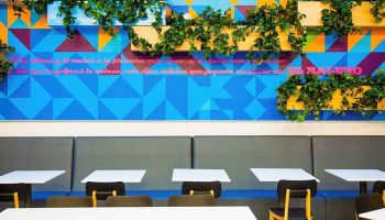 Ibis Styles Mexico Reforma's gay-friendly dining area. Colorful geometric wall art with plants, tables and chairs. Modern design.