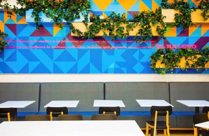 Ibis Styles Mexico Reforma's gay-friendly dining area. Colorful geometric wall art with plants, tables and chairs. Modern design.