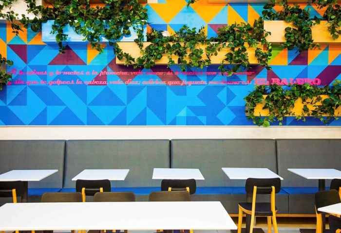 Ibis Styles Mexico Reforma's gay-friendly dining area. Colorful geometric wall art with plants, tables and chairs. Modern design.