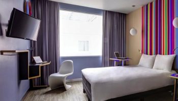 Ibis Styles Mexico Reforma hotel room. Modern design, colorful accents, TV, desk, and bed. Gay-friendly stay in Mexico City.
