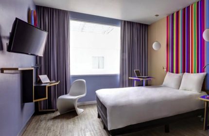 Ibis Styles Mexico Reforma hotel room. Modern design, colorful accents, TV, desk, and bed. Gay-friendly stay in Mexico City.