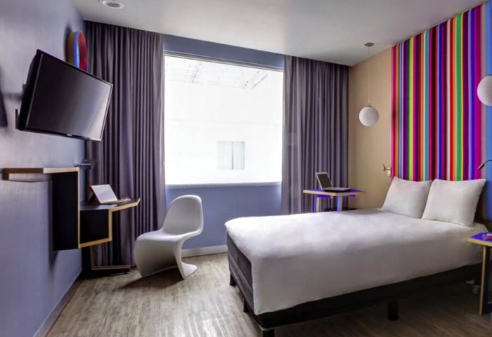 Ibis Styles Mexico Reforma hotel room. Modern design, colorful accents, TV, desk, and bed. Gay-friendly stay in Mexico City.