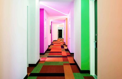 Hallway at Ibis Styles Mexico Reforma, a gay-friendly hotel. Colorful walls, carpet, and modern lighting. Gay travel in Mexico City.