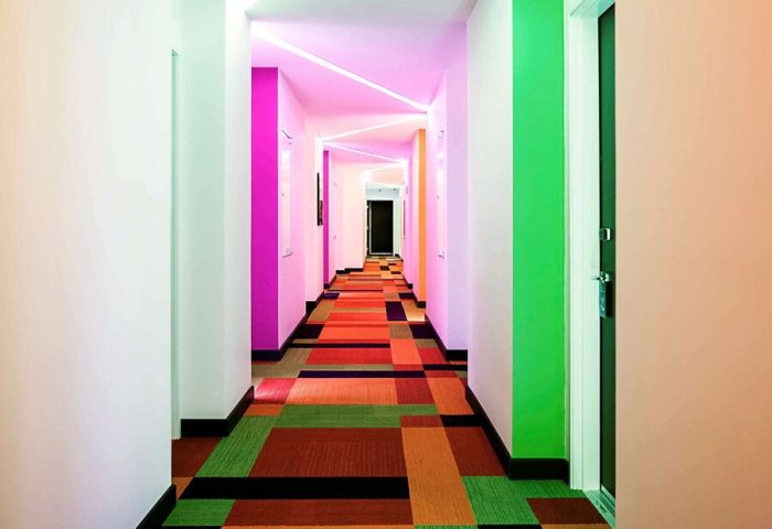 Hallway at Ibis Styles Mexico Reforma, a gay-friendly hotel. Colorful walls, carpet, and modern lighting. Gay travel in Mexico City.