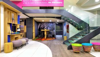Ibis Styles Mexico Reforma's gay-friendly hotel lobby. Modern design with colorful accents, stairs, and seating areas. A welcoming space for gay travelers.