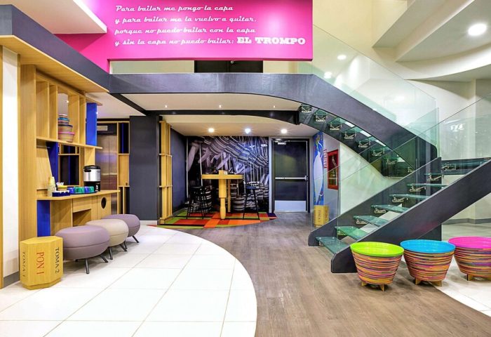 Ibis Styles Mexico Reforma's gay-friendly hotel lobby. Modern design with colorful accents, stairs, and seating areas. A welcoming space for gay travelers.