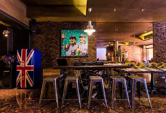 Inhouse Boutique gay-friendly hotel interior. Union Jack fridge, brick wall, and bar stools. Gay travel advice.