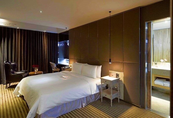 Inhouse Boutique gay-friendly hotel room. Bedroom with bed, chair, and bathroom. Gay travel accommodations with modern design.