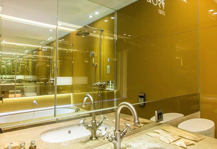 Inhouse Boutique gay-friendly hotel bathroom. Modern design with gold accents, glass shower, and double sinks. Luxury travel for gay men.