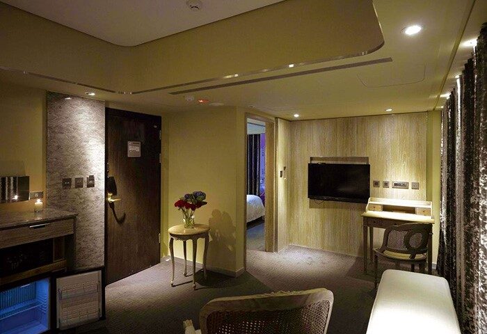 Inhouse Hotel room interior. Gay-friendly hotel features include a desk, TV, mini-fridge, and view into the bedroom. Modern design.