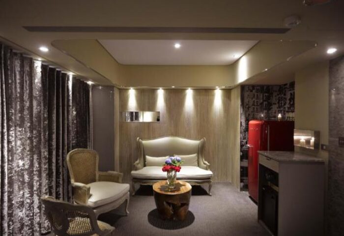 Inhouse Hotel room interior. Gay-friendly hotel with seating area, red refrigerator, and modern design. Ideal for gay travel and comfortable stays.