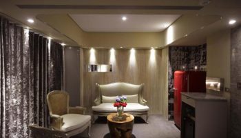 Inhouse Hotel room interior. Gay-friendly hotel with seating area, red refrigerator, and modern design. Ideal for gay travel and comfortable stays.