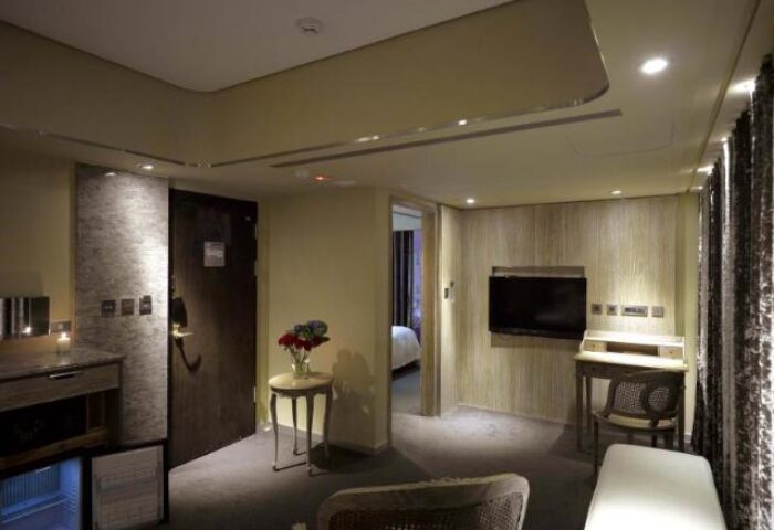 Inhouse Hotel room interior. Gay-friendly hotel with a modern design, featuring a desk, seating area, and a glimpse into the bedroom.