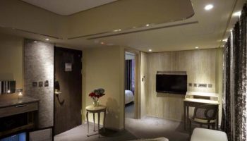 Inhouse Hotel room interior. Gay-friendly hotel with a modern design, featuring a desk, seating area, and a glimpse into the bedroom.