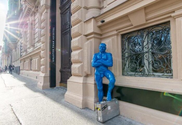 meetme23 gay-friendly hotel: Blue male statue with suitcase outside. Pet-friendly accommodation for gay men travelers.