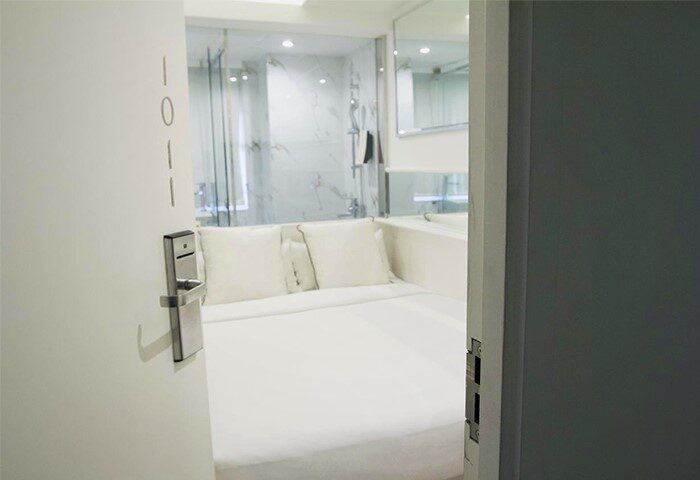 Mini Hotel Central room interior. Gay-friendly hotel with bed, white linens, and shower. Modern design for gay men travelers.