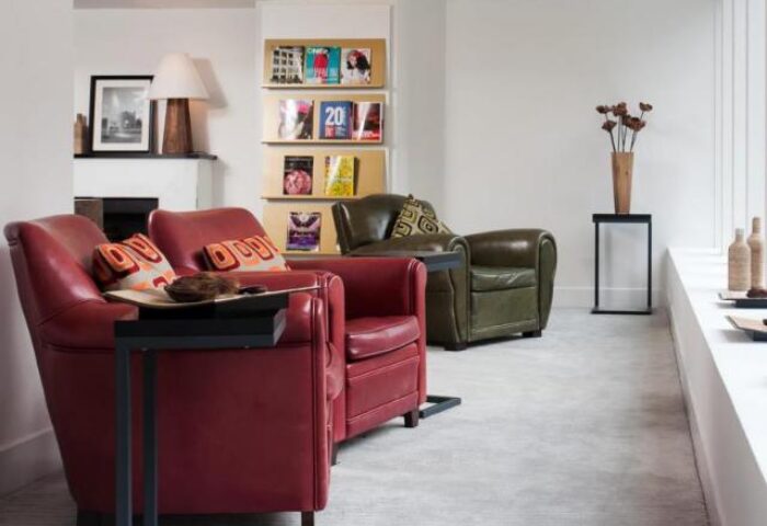 Mini Hotel Central interior. Gay-friendly hotel lounge area with red and green leather armchairs, magazines, and modern decor.