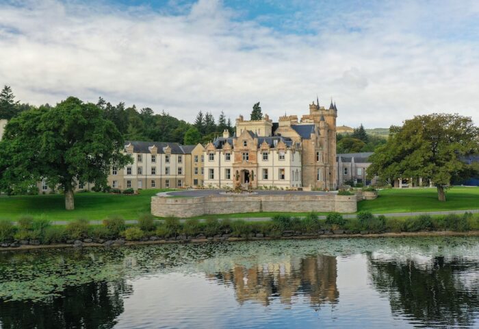 Cameron House on Loch Lomond, a gay-friendly hotel. Scottish architecture reflected in the loch's water. A luxury travel destination.