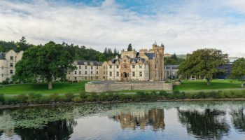 Cameron House on Loch Lomond, a gay-friendly hotel. Scottish architecture reflected in the loch's water. A luxury travel destination.