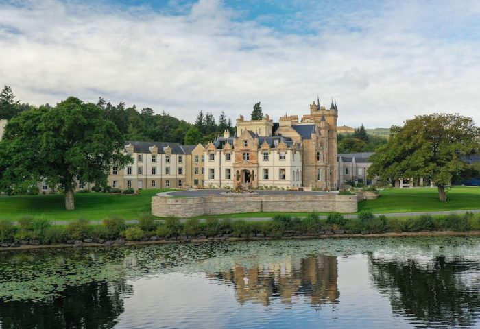 Cameron House on Loch Lomond, a gay-friendly hotel. Scottish architecture reflected in the loch's water. A luxury travel destination.