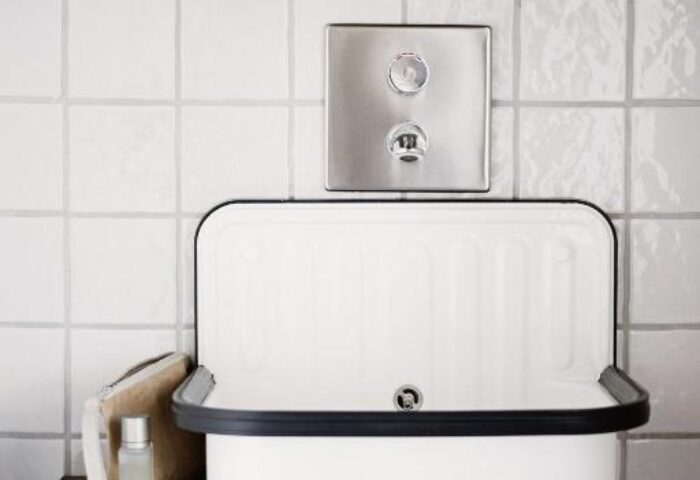 Room007 Chueca Hostel bathroom. Gay-friendly hotel sink with a mirror, brick wall, and white tiles. Ideal for gay travel in Madrid, Spain.