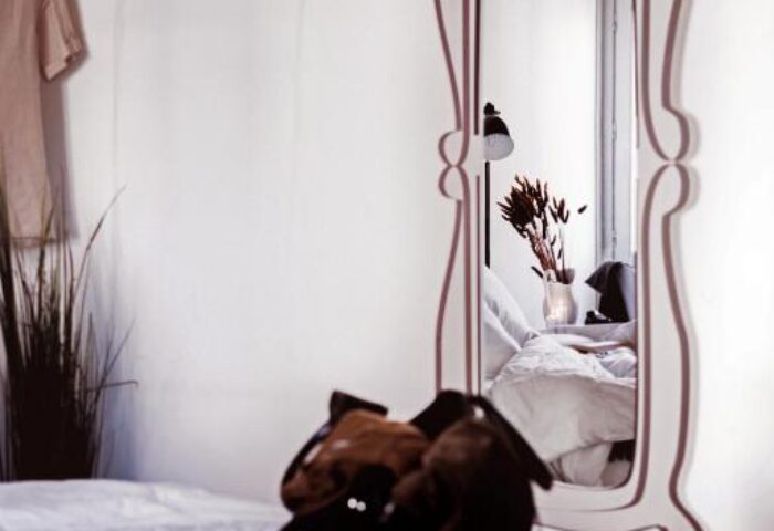 Room at room007 Chueca Hostel, a gay-friendly hotel. Features a bed with a bag on it and a mirror. Gay travel in Madrid, Spain.