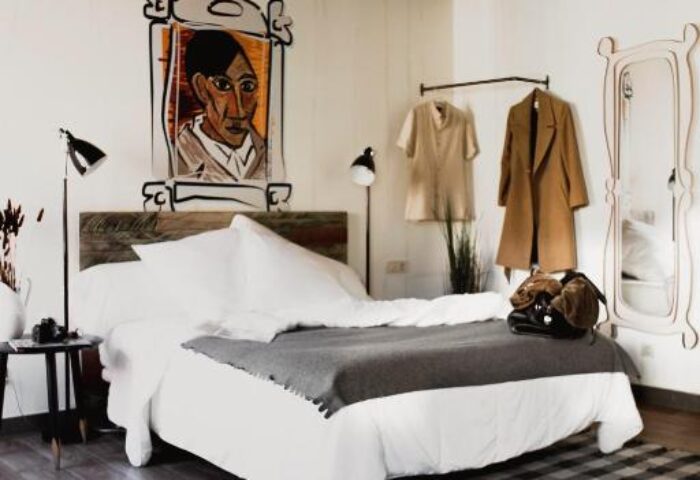 Room007 Chueca Hostel gay-friendly room. Bed with white linens, gray blanket, and artwork. Modern design for gay travelers in Chueca, Madrid.