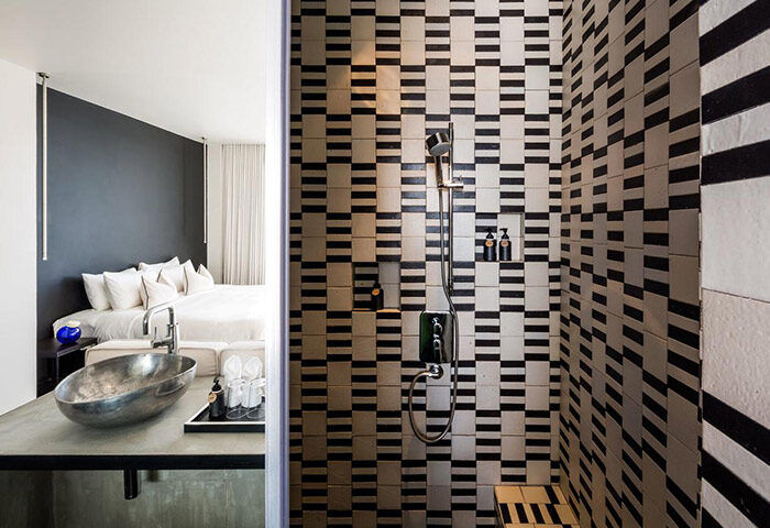 Bathroom at sala rattanakosin Bangkok, a gay-friendly hotel. Shower with black and white tiles. Bedroom and sink visible. Gay travel.