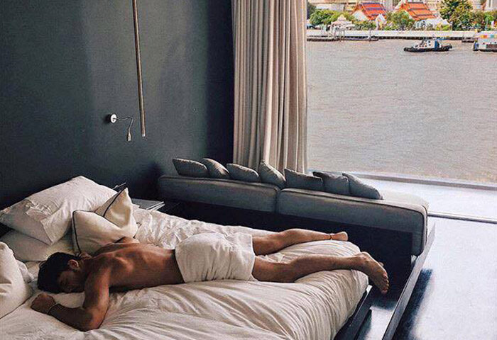 Gay-friendly sala rattanakosin Bangkok hotel. Man relaxing in room with river view. Luxury gay travel in Thailand.