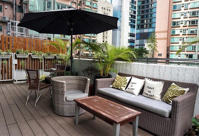 The Figo gay-friendly hotel patio. Outdoor seating area with sofa, chairs, table, and umbrella. Plants add a touch of nature to this urban retreat.