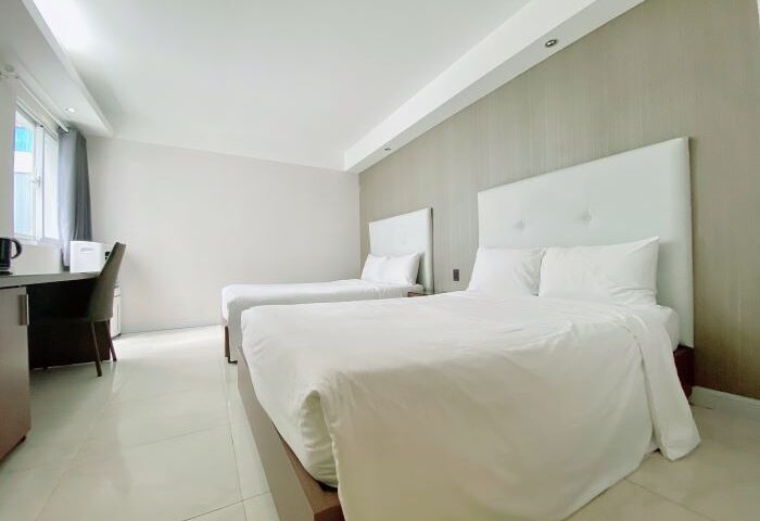 The Luxe Hotel, Ho Chi Minh City: Two beds with white linens, desk and chair. Gay-friendly hotel room interior. Modern, clean design.