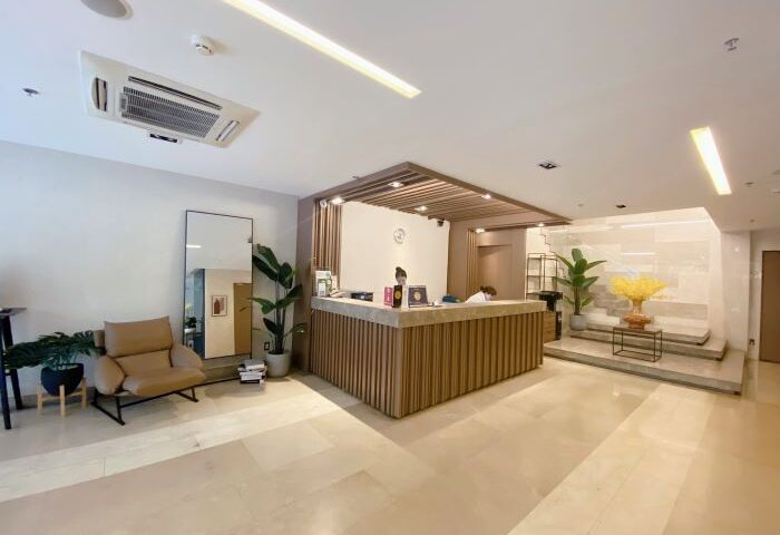 The Luxe Hotel lobby in Ho Chi Minh. Modern design with wood accents, plants, and a seating area. Gay-friendly hotel interior.