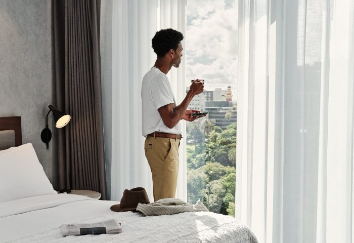 Le Meridien Melbourne hotel room view. Gay hotel in Collingwood. Man enjoying the view with a coffee. Gay travel advice.