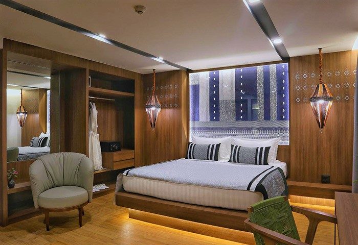 Nimman Chiang Mai gay-friendly hotel room. Modern luxury design with wooden accents, stylish lamps, and comfortable bed. Ideal for gay travelers.