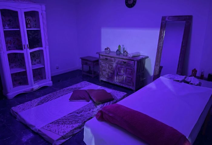 Gay massage in Gran Canaria. Massage room with bed, floor mattress, cabinet, dresser, and mirror. Blue lighting. Gay travel advice.