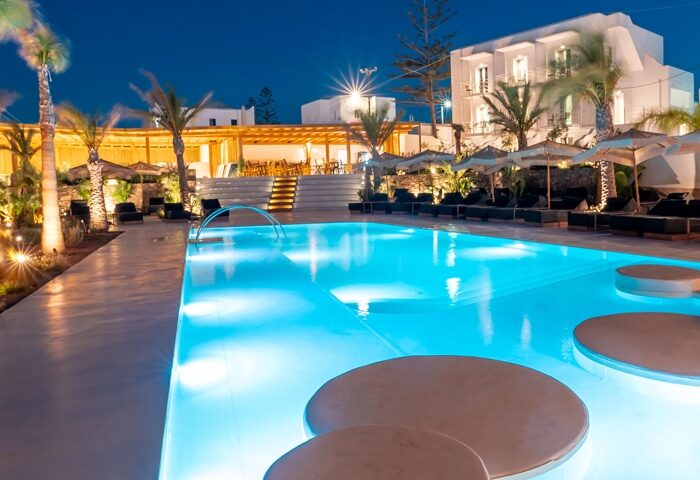 Akkadian Hotel, a gay-only hotel in Mykonos for gay couples. Illuminated pool and lounge area at night. Luxury gay travel destination.