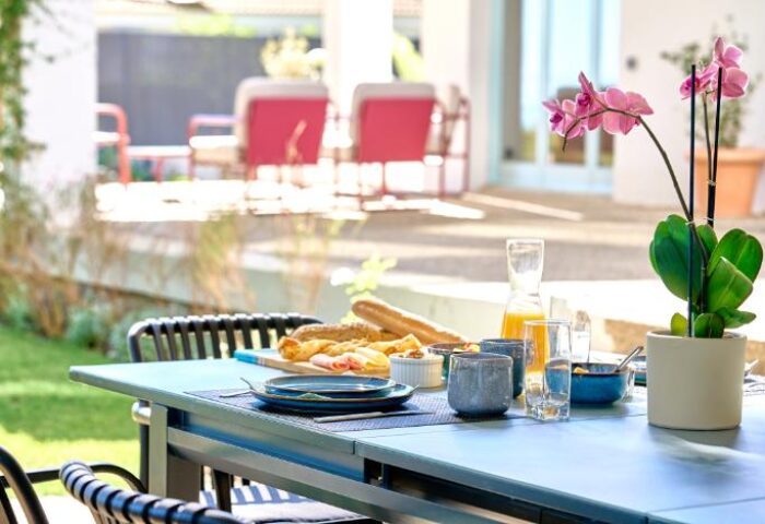 Casa Brisa Boutique Guest House: Outdoor dining at this gay-owned guest house. Table setting with food, drinks, and an orchid centerpiece.