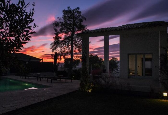 Casa Brisa Boutique Guest House at dusk. Gay-owned villa with pool, lounge chairs, and colorful sky. Ideal for gay men travel.