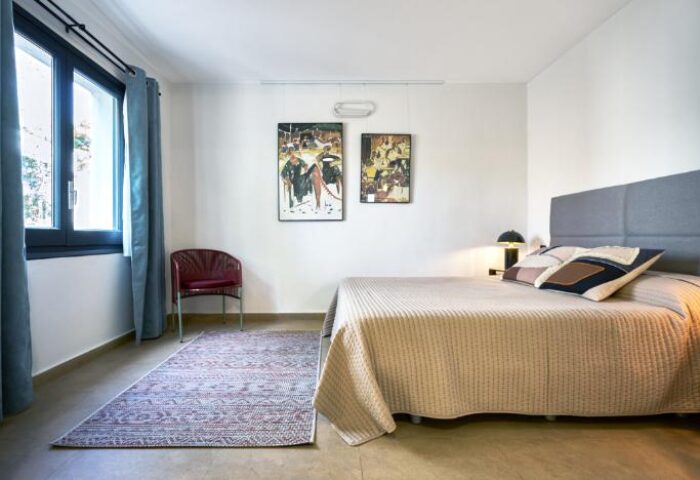 Casa Brisa Boutique Guest House bedroom. Gay-owned guest house room with bed, art, chair, rug, and window. A stylish space for gay travelers.