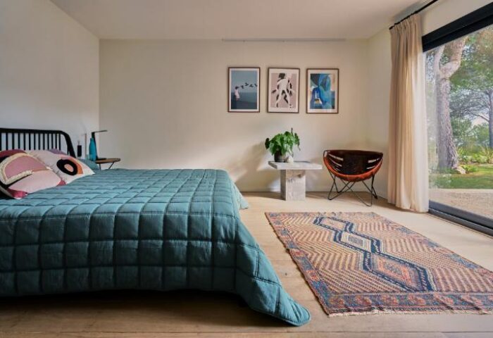 Casa Brisa Boutique Guest House bedroom. Gay-owned guest house with a bed, rug, chair, art, and view to the outside. Gay travel.