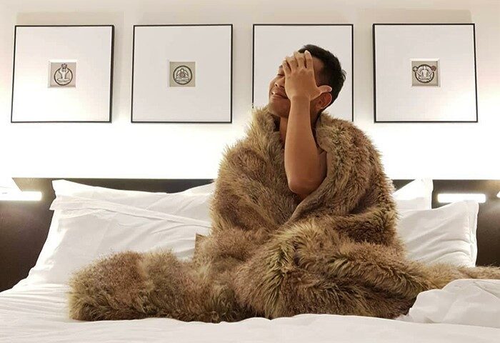 Gay party at The Resident Soho hotel in London. Man covered with fur blanket on a bed in The Nadler Soho. Gay travel advice.