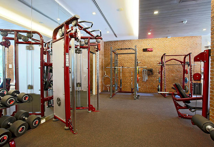 Gym at Renaissance Phuket Resort & Spa. Fitness center with weights, machines, and brick wall. Gay-friendly beach resort for men's travel.