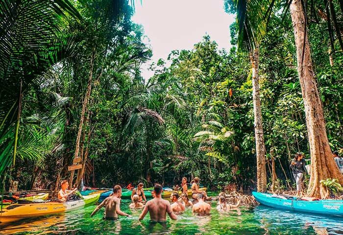 Gay Slumber Party at The Beach Hostel, Ao Anang. Men kayaking in a jungle river. Popular beachfront hotel for gay travelers.
