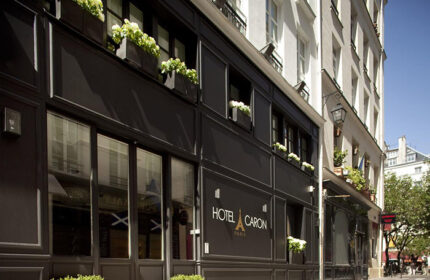 Hotel Caron facade, gay-popular hotel in Paris' gayborhood. Chic black exterior with flower boxes. A great choice for gay travelers.
