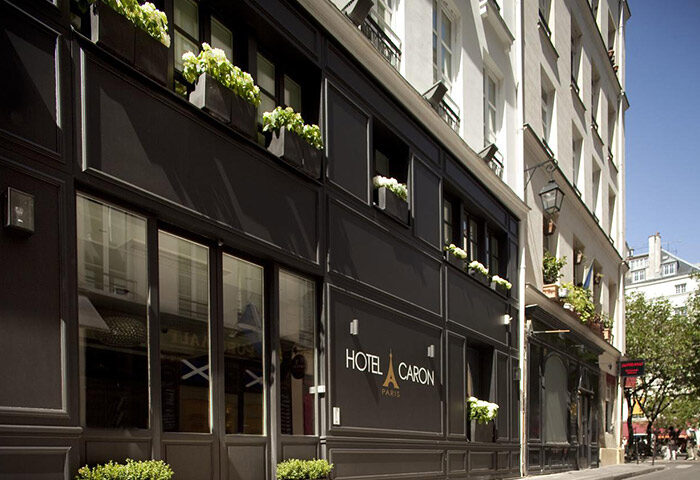 Hotel Caron facade, gay-popular hotel in Paris' gayborhood. Chic black exterior with flower boxes. A great choice for gay travelers.