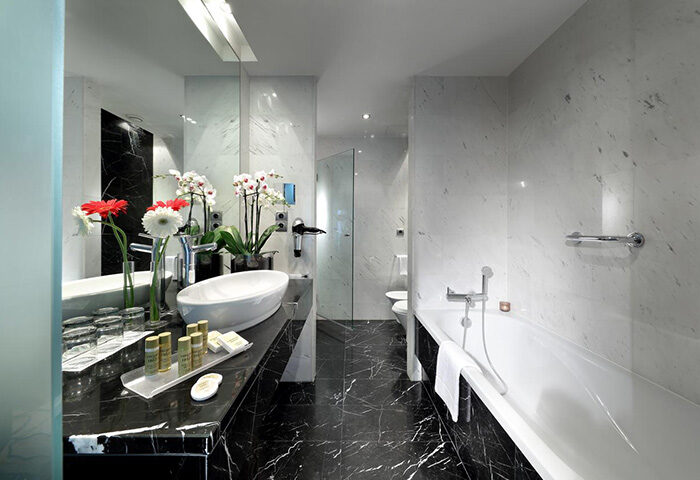 Eurostars Hotel das Letras bathroom. Gay-popular hotel room in Lisbon's gayborhood. Marble walls, black countertop, and bathtub.