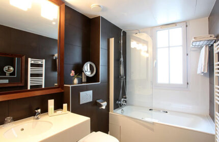 Bathroom at Little Palace Hotel, a gay-popular hotel in Paris' Marais gayborhood. Features a sink, toilet, bathtub, shower, and mirror.